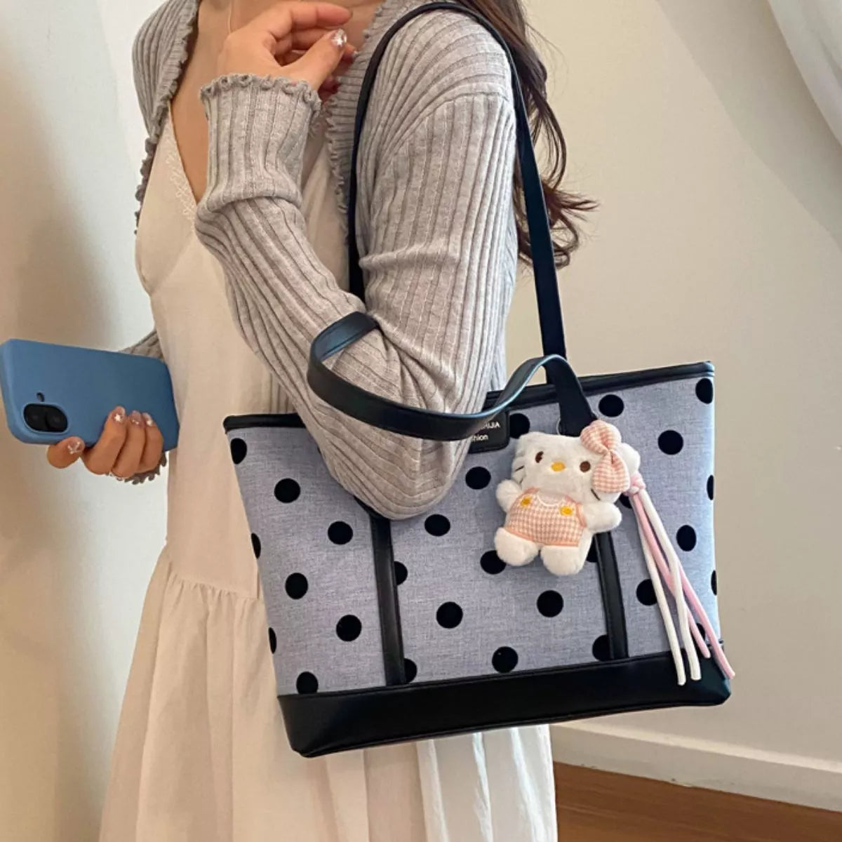 Medium polka dot shoulder bag with cute keychain, carried by a woman in a stylish outfit, showcasing its trendy design.