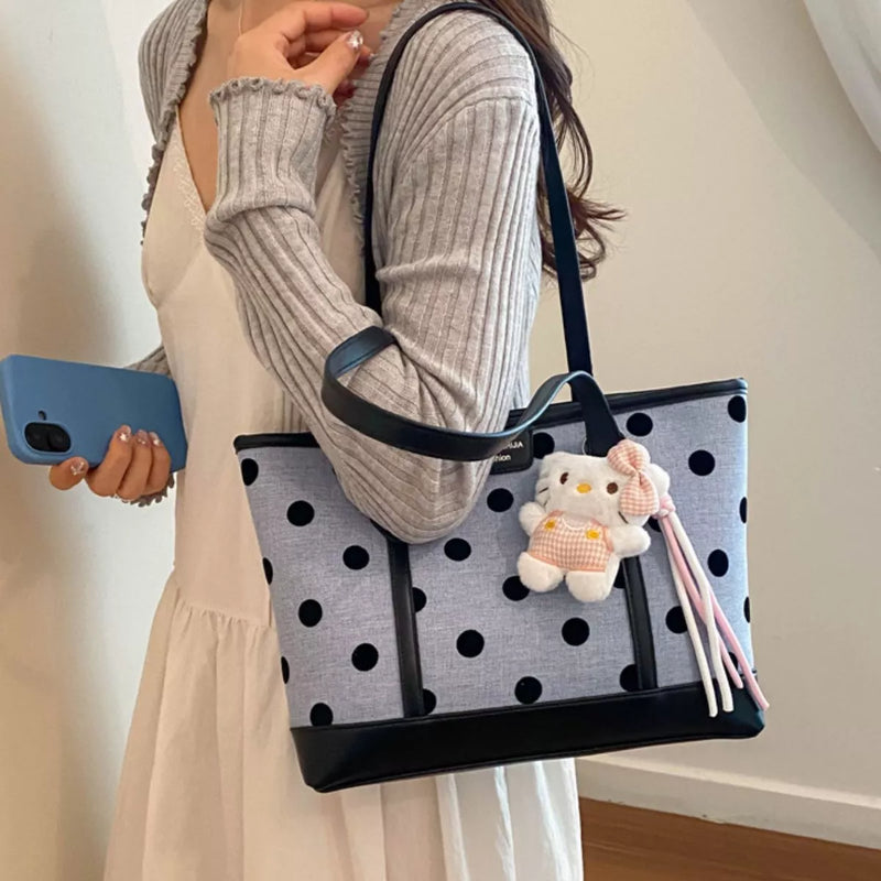 Medium polka dot shoulder bag with cute keychain, carried by a woman in a stylish outfit, showcasing its trendy design.