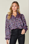 Model wearing metallic purple balloon sleeve shirt with colorful print and black pants.