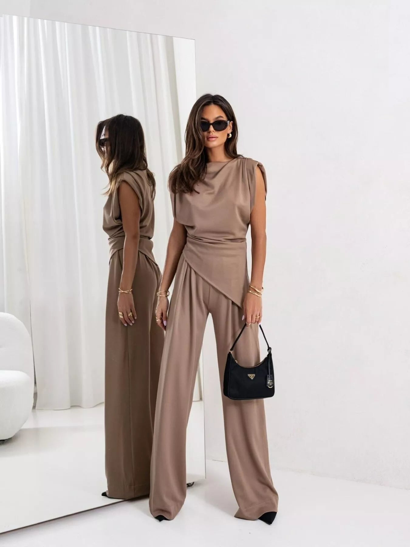 Model wearing a satin cowl neck top and pants set, showcasing elegance and style in a modern setting.