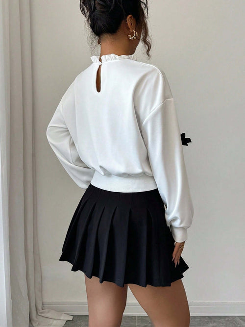 Model wearing Bow Decor Dropped Shoulder Sweatshirt paired with a black pleated skirt, showcasing stylish details.