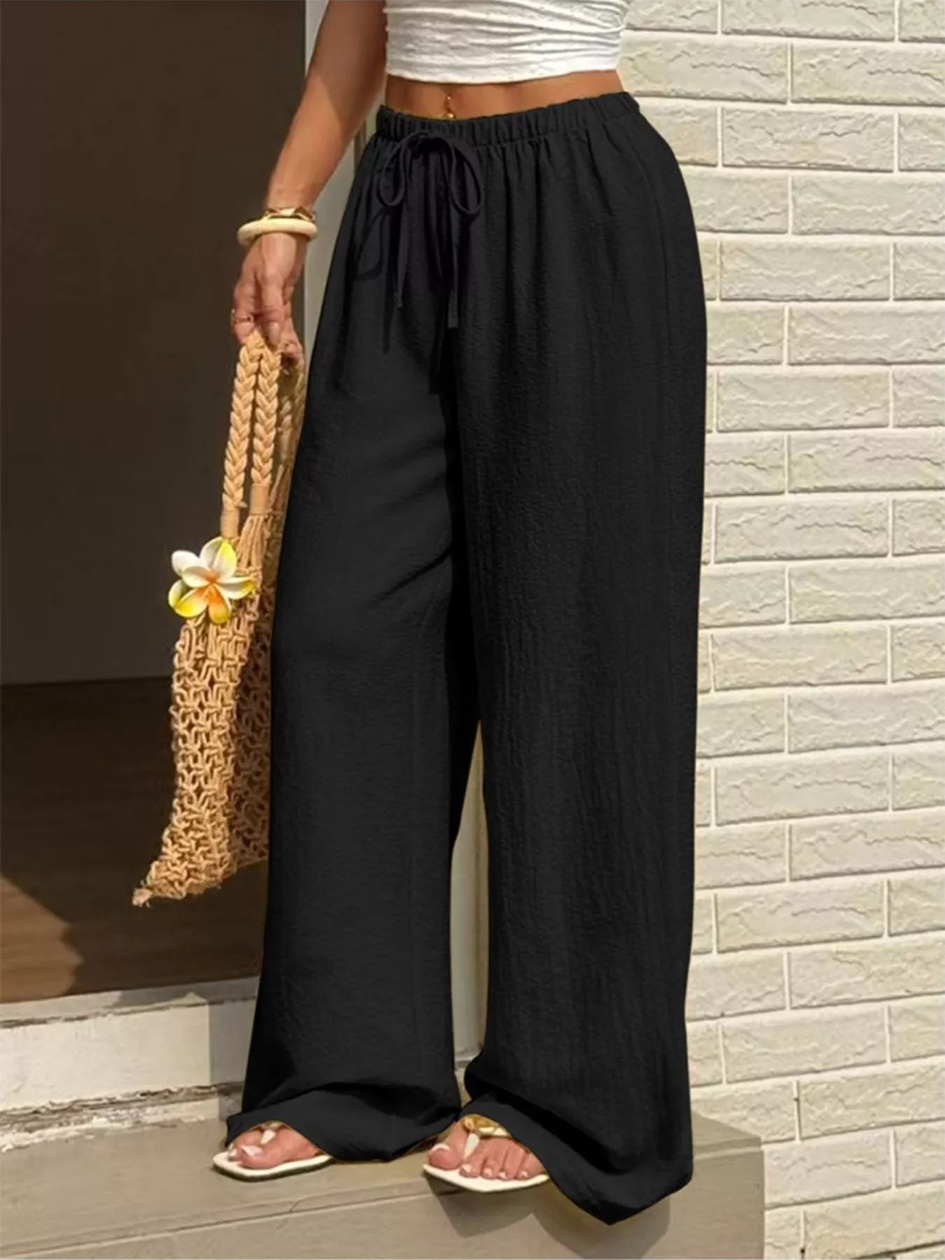 Model wearing plus size wide leg pants with an adjustable drawstring, paired with a stylish tote bag.
