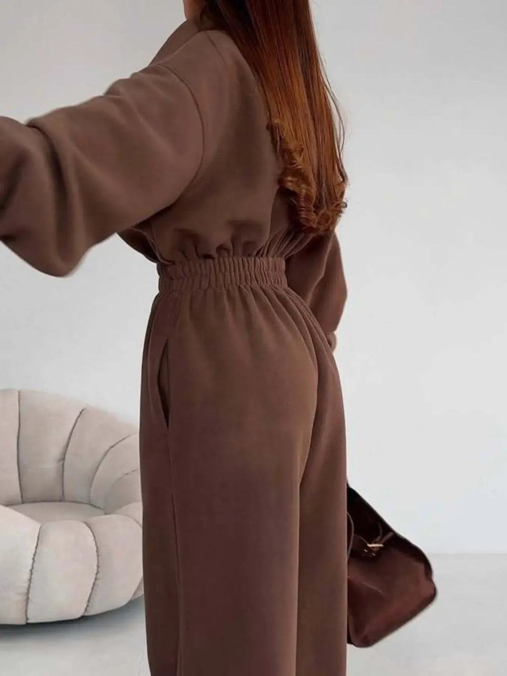Model showcasing the women's jumpsuit with a zip front and long sleeves in brown, featuring a comfortable elastic waist.