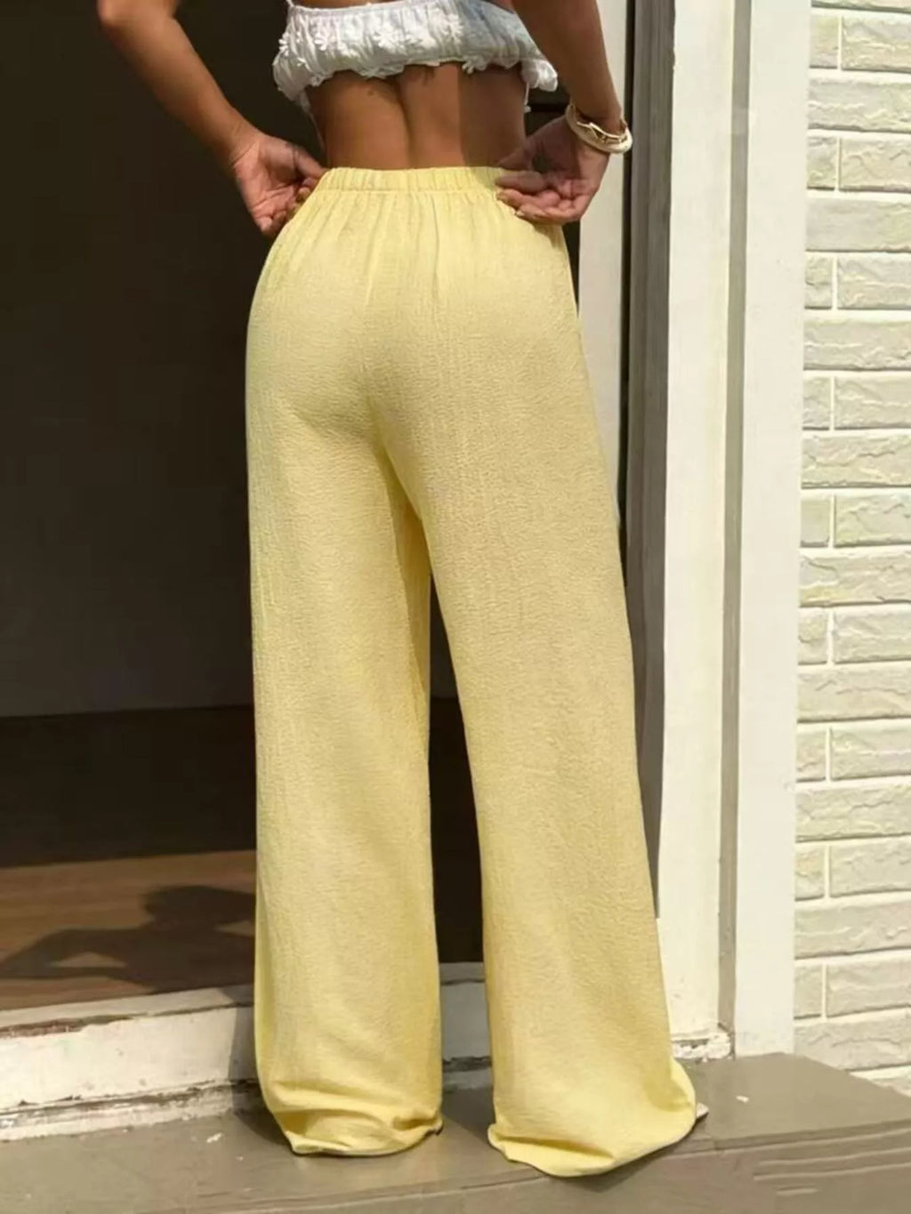 Plus size wide leg pants in soft yellow, featuring a high waist and adjustable drawstring for comfort and style.