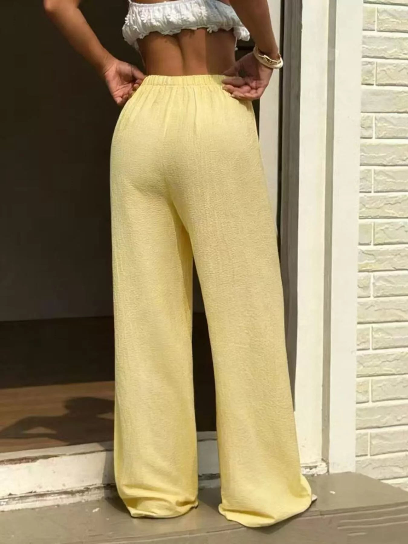 Plus size wide leg pants in soft yellow, featuring a high waist and adjustable drawstring for comfort and style.