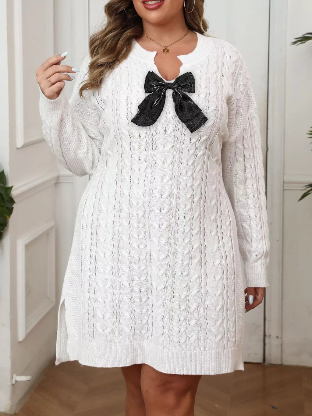 Plus size sweater dress featuring cable knit texture and a contrast bow detail, offering comfort and style.