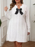 Plus size sweater dress featuring cable knit texture and a contrast bow detail, offering comfort and style.