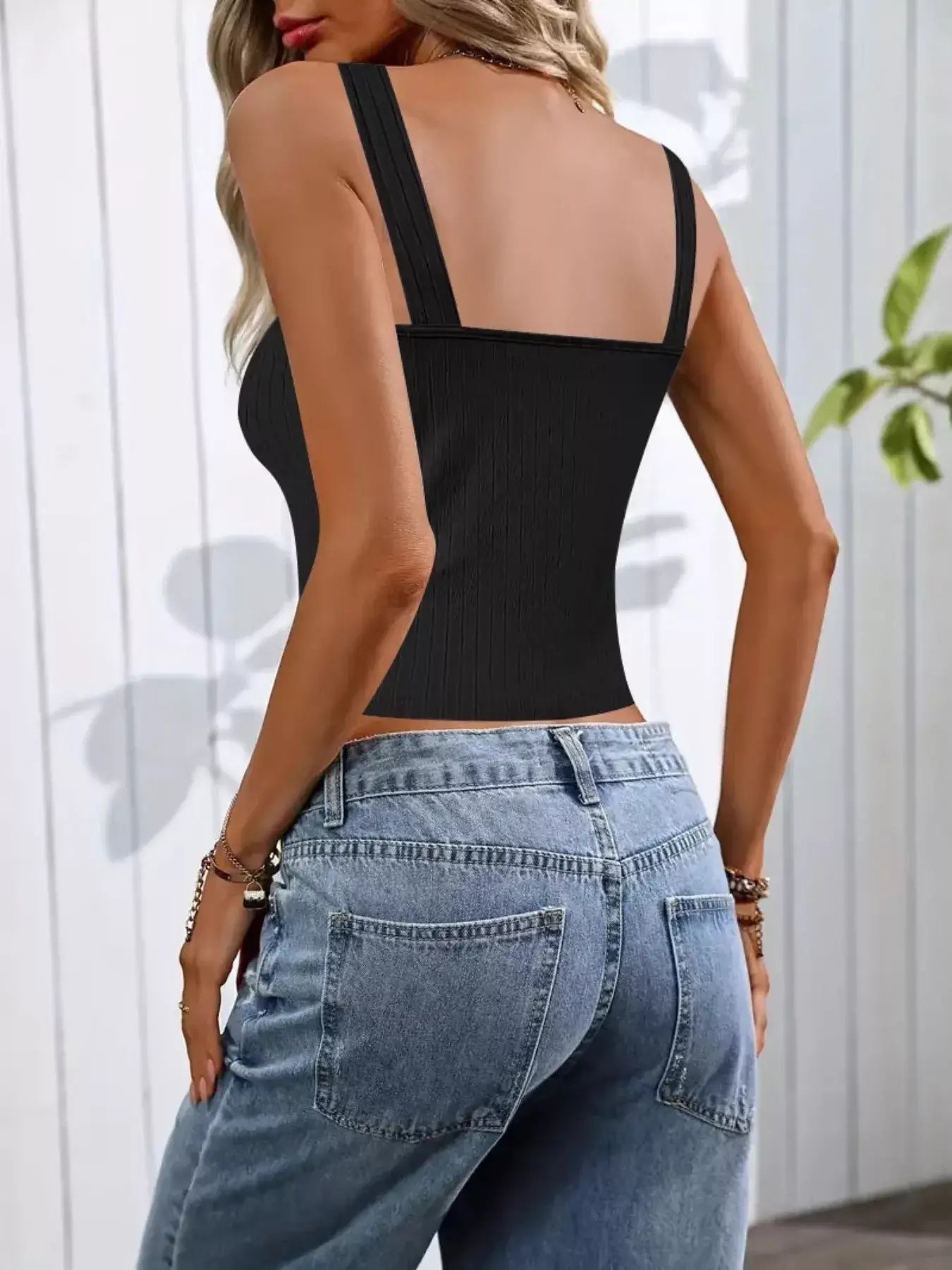 Woman wearing a back view of a black Pearl Detail Scoop Neck Tank with high-waisted jeans.