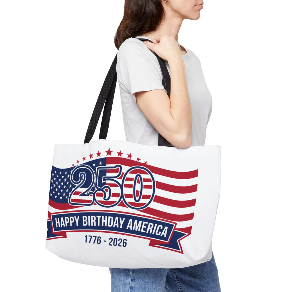 Woman holding a patriotic tote bag featuring red, white, and blue design with '250 Happy Birthday America 1776–2026'.