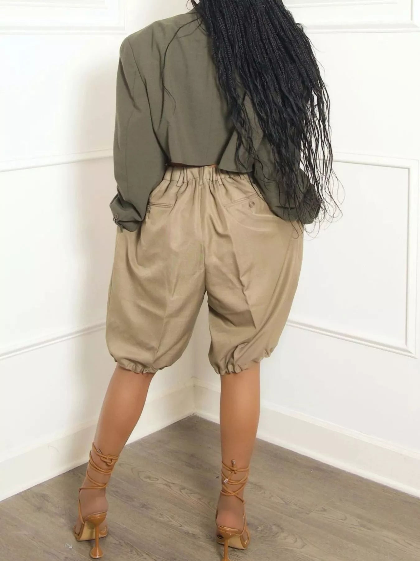 Back view of woman wearing high-waisted women's pleated shorts paired with a loose top and stylish sandals.