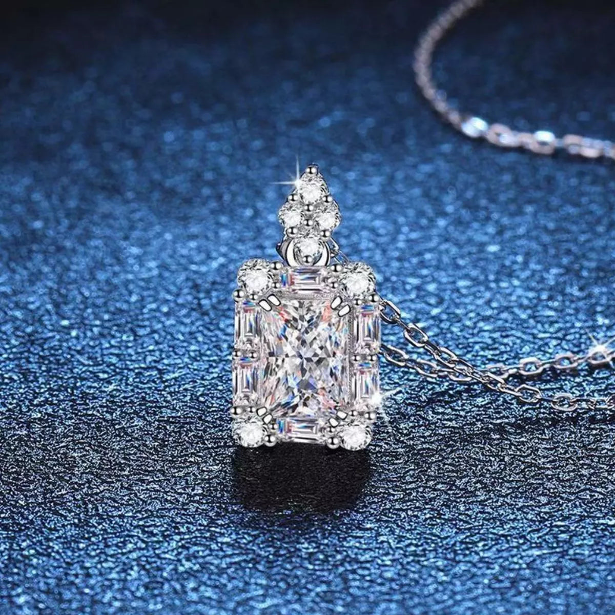 Moissanite jewelry 1 carat pendant necklace on a blue background, showcasing brilliance and elegance.