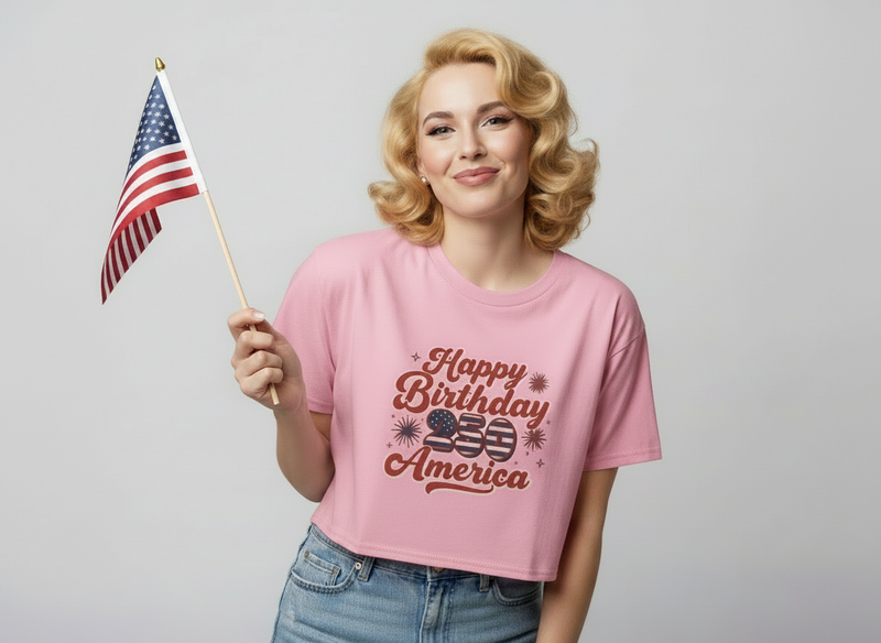Happy 250th Birthday America Women's Crop Tee worn by a woman holding a small American flag, showcasing a playful style.