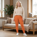Model wearing Swageye Sun-Kissed Leo Constellation Leggings - Exclusive Plus Size with a cozy sweater in a bright living room.