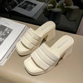 Open Toe Block Heel Sandals in cream color with padded straps and block heels on a stylish table.