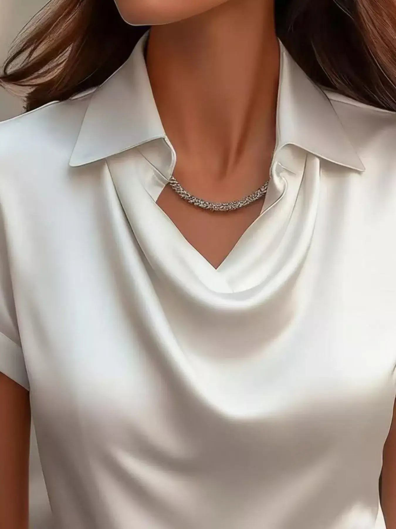 Plus size elegant clothing featuring a shimmery blouse with a cowl neckline and a stylish necklace.
