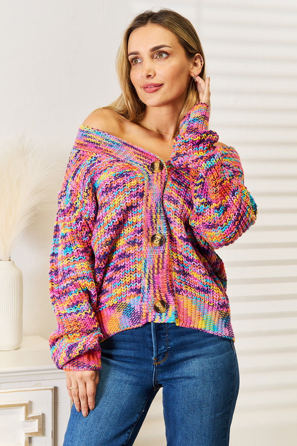 Long sleeve cardigan in colorful knit with buttons, styled casually, showcasing an off-shoulder look and vibrant design.