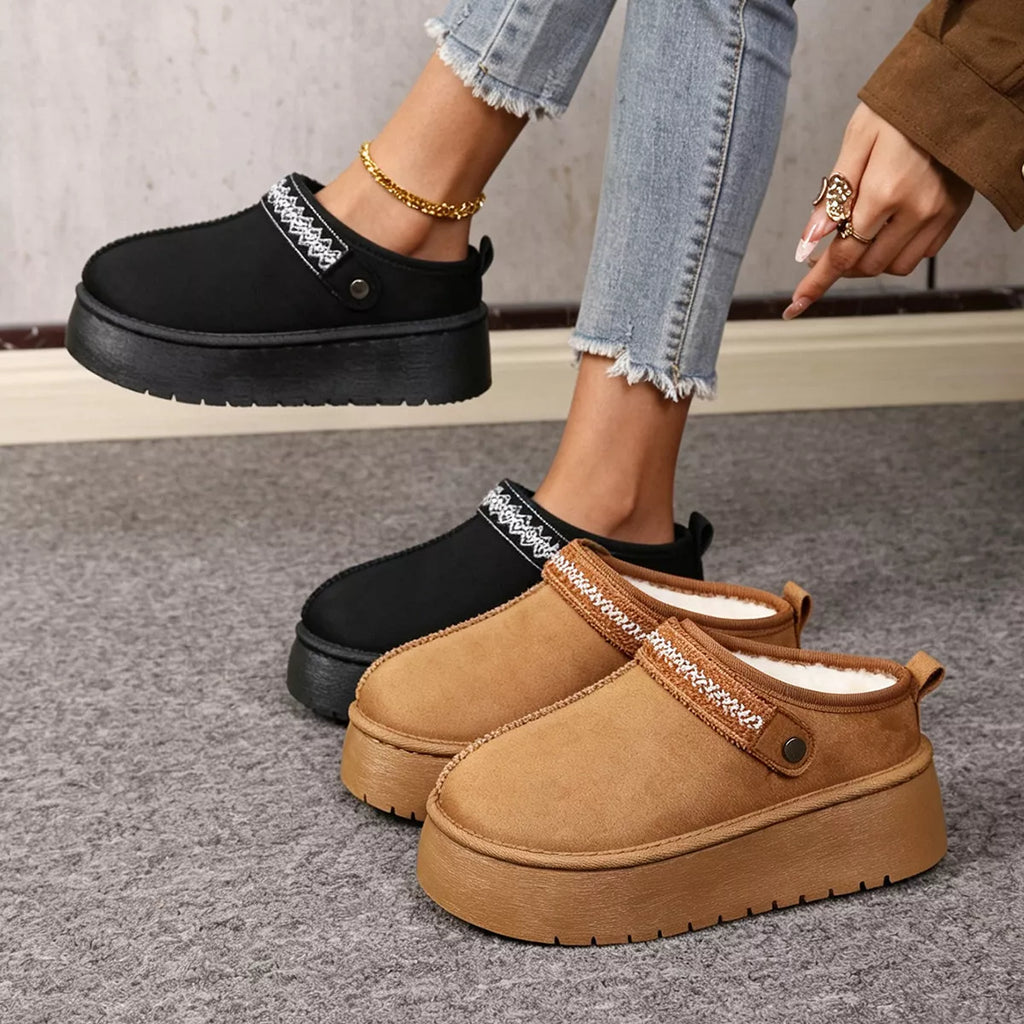 Stylish suede boots in black and tan with fur lining, showcasing platform design and chic detailing.