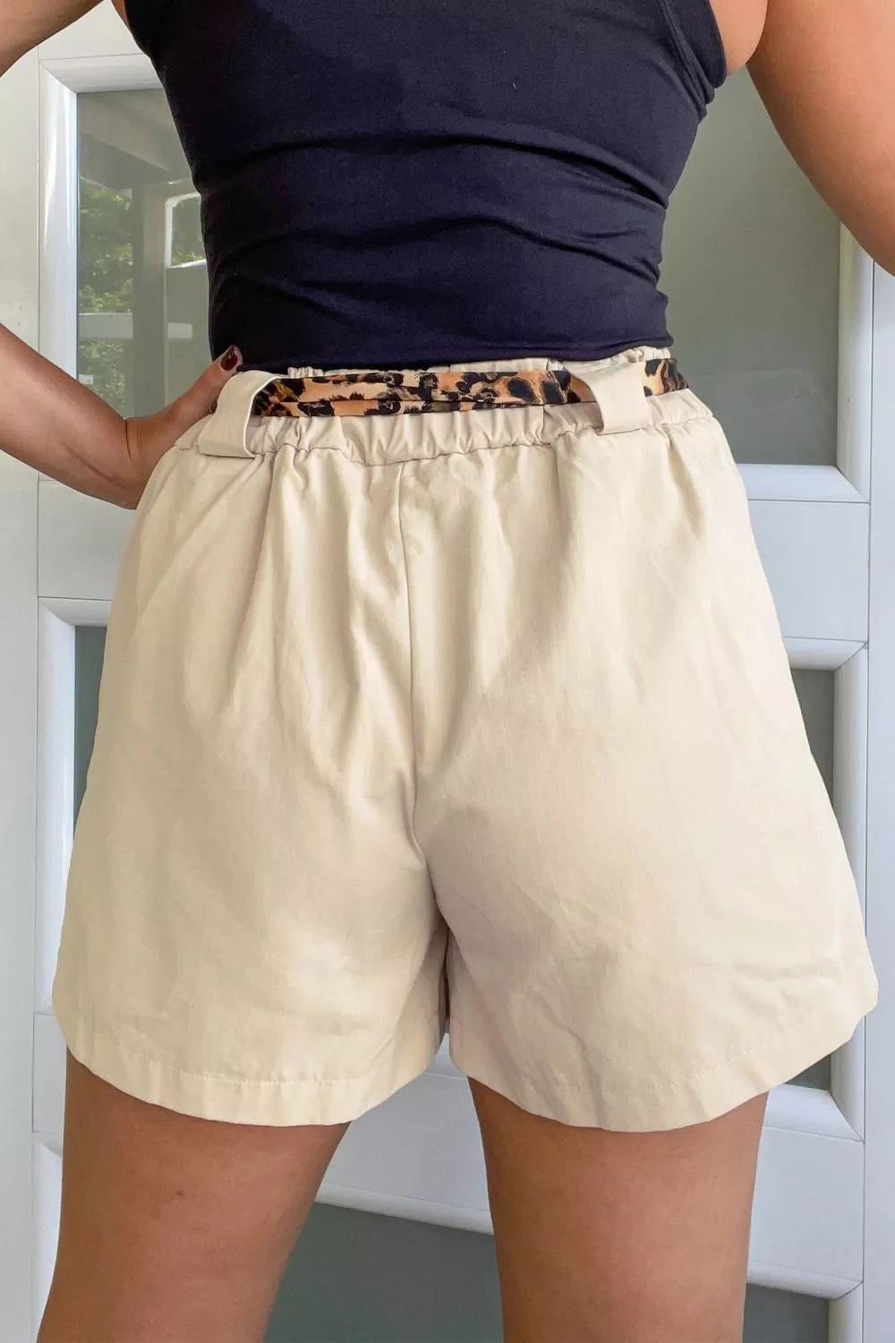 Back view of tailored pleated shorts with a belted design and a stylish waistband detail.