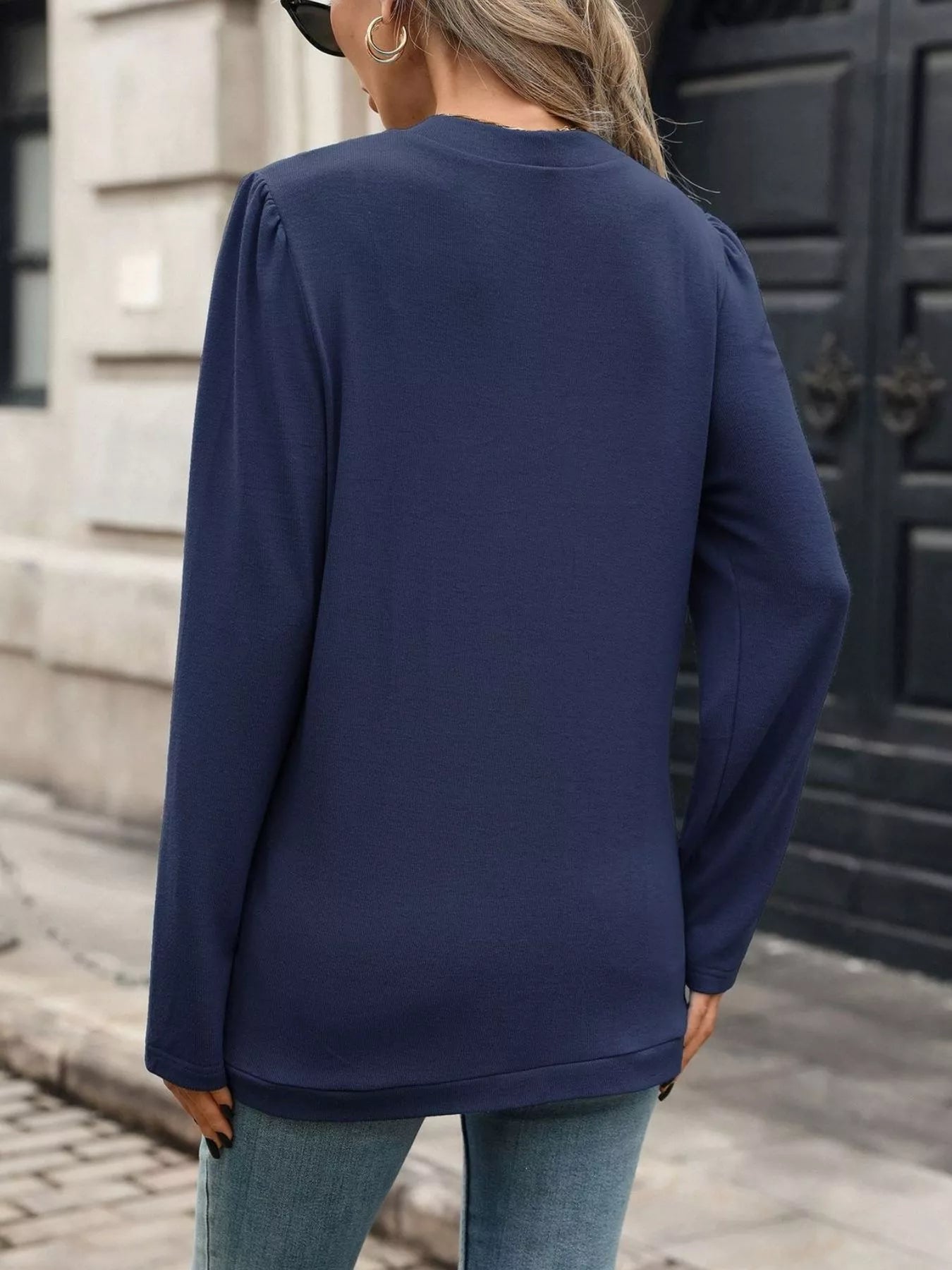 Back view of a woman wearing a thin open front cardigan in navy, styled with blue jeans.