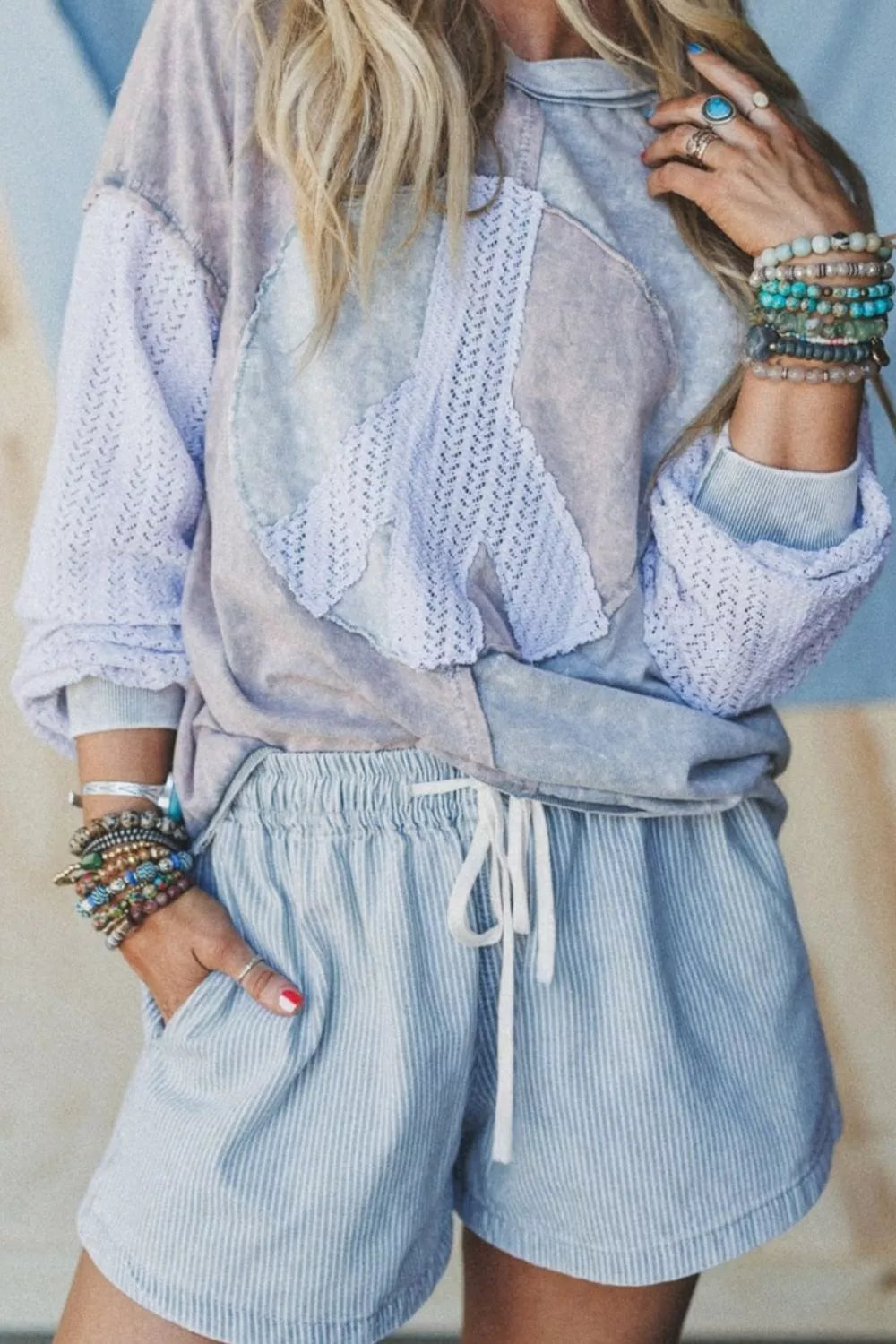 Fashionable woman wearing striped drawstring shorts and a stylish top with boho accessories.