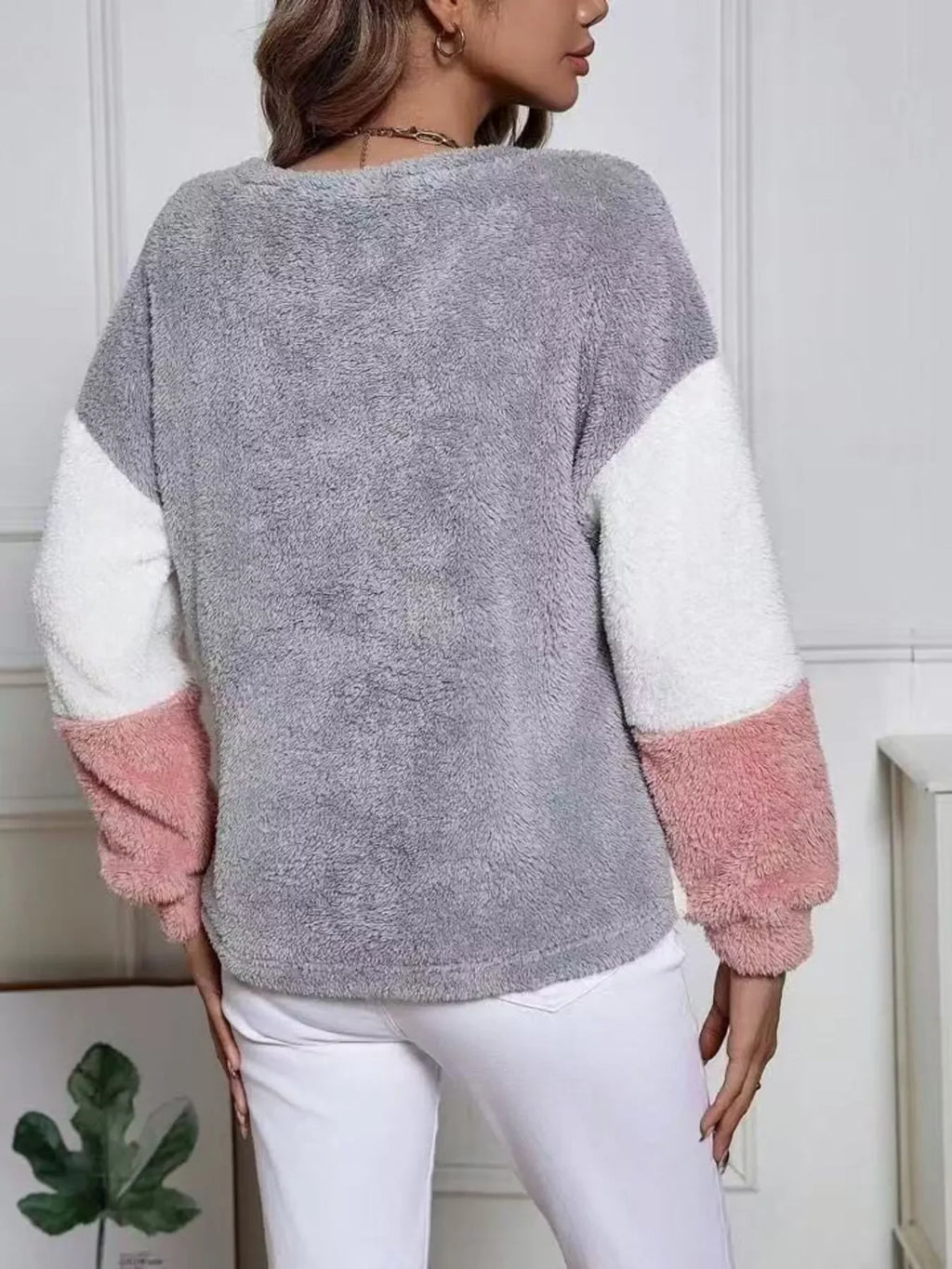 Back view of a woman wearing a pink grey fuzzy knit sweatshirt with color block design.