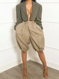 Stylish woman wearing high-waisted women's pleated shorts with a cropped blazer and strappy heels.