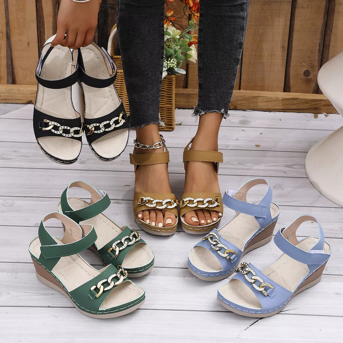 Open toe wedge sandals in black, brown, green, and blue with chain accents displayed outdoors.