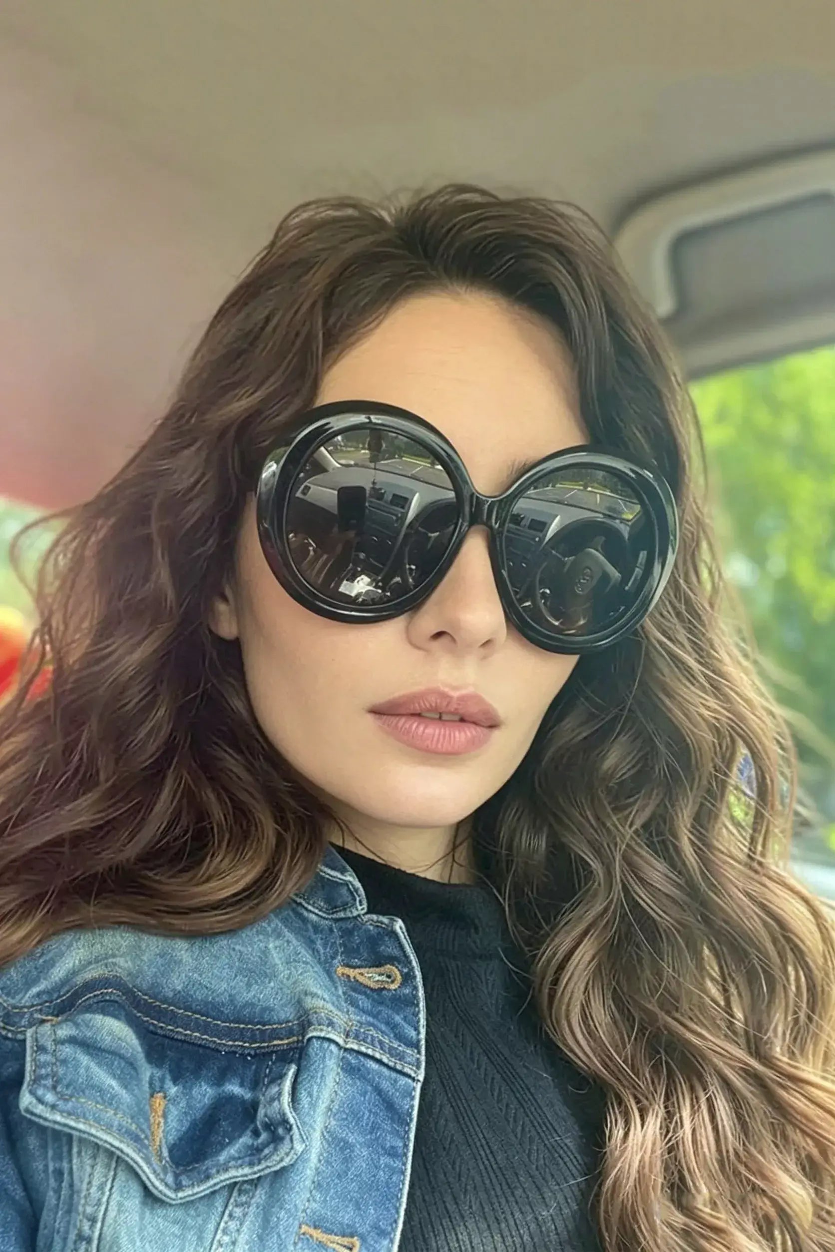 Woman wearing oversized sunglasses for women with round frame style while inside a car.