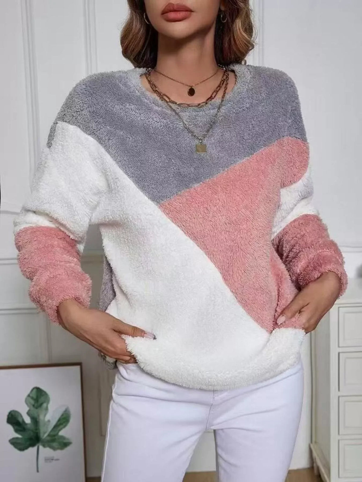 Model wearing a pink grey fuzzy knit sweatshirt with a playful color block design in a stylish setting.