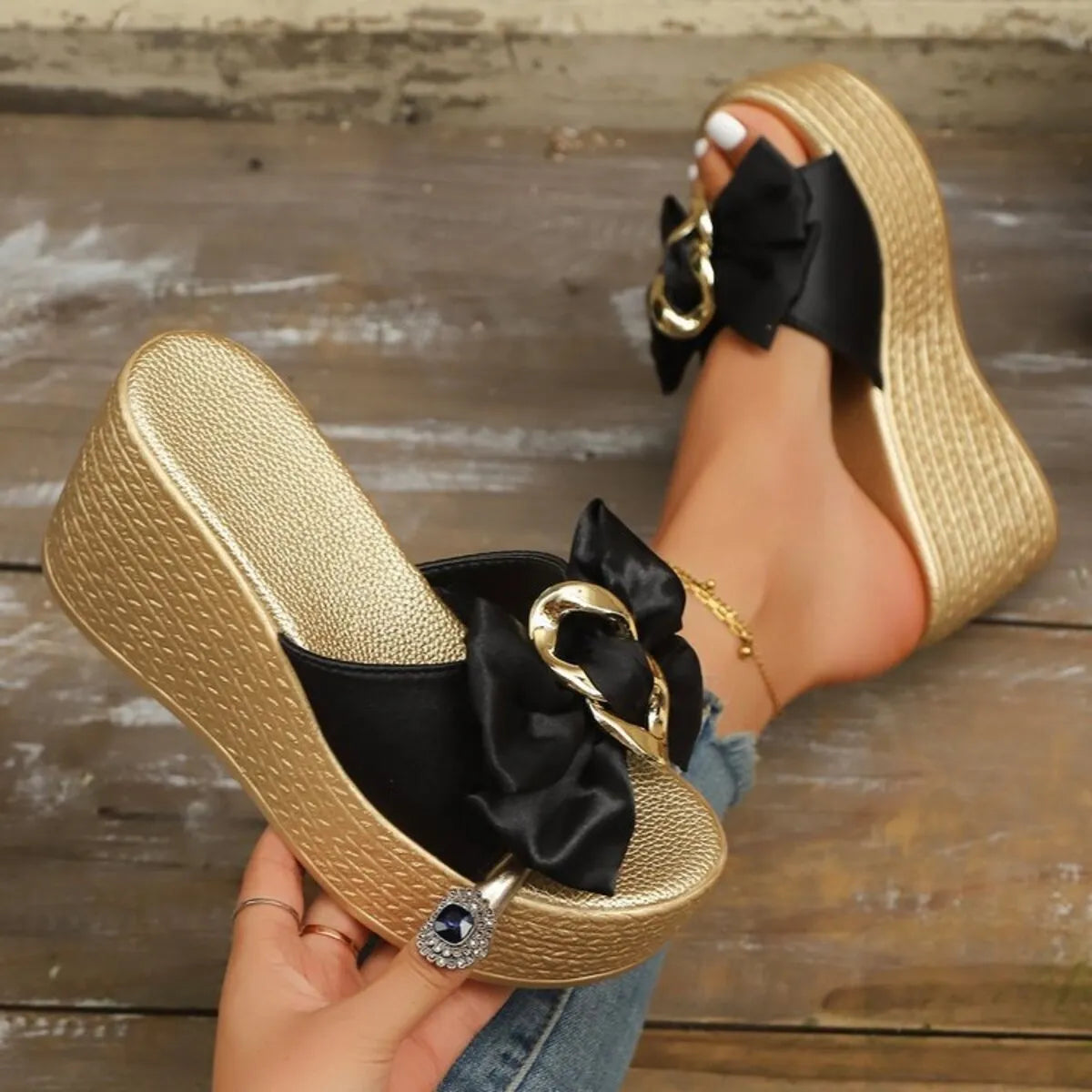 Wedge sandals with bow featuring a black bow and gold wedge heel, perfect for stylish summer outings.