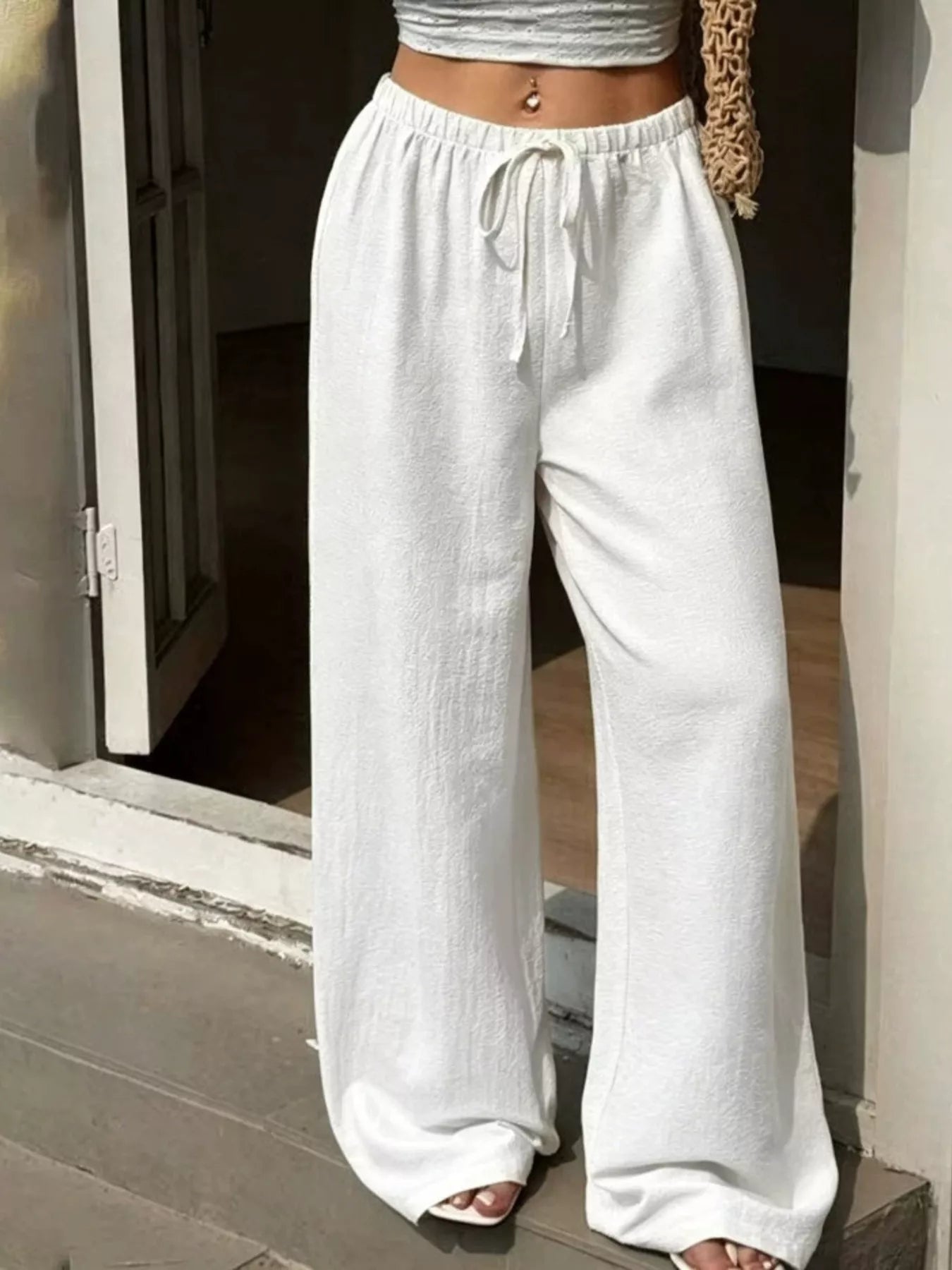 Plus size wide leg pants in white color, featuring a high waist and adjustable drawstring for a customizable fit.