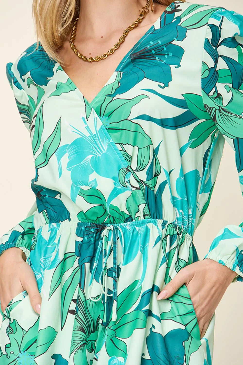 Close-up of a model wearing a women's floral romper with green floral patterns and pockets.