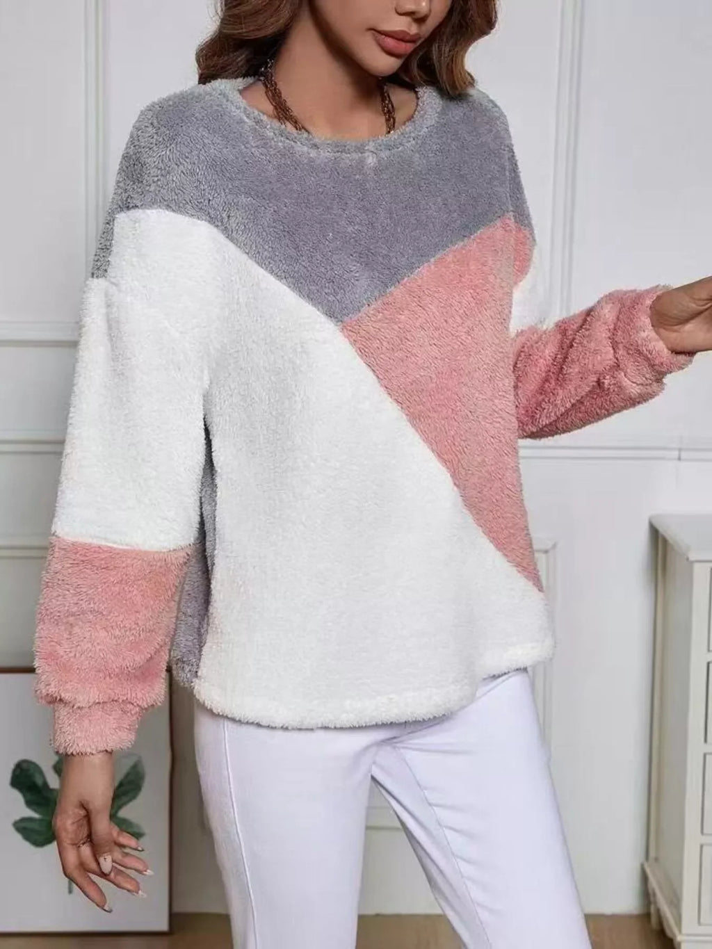 Woman wearing a pink grey fuzzy knit sweatshirt featuring color block design and soft, cozy fabric.