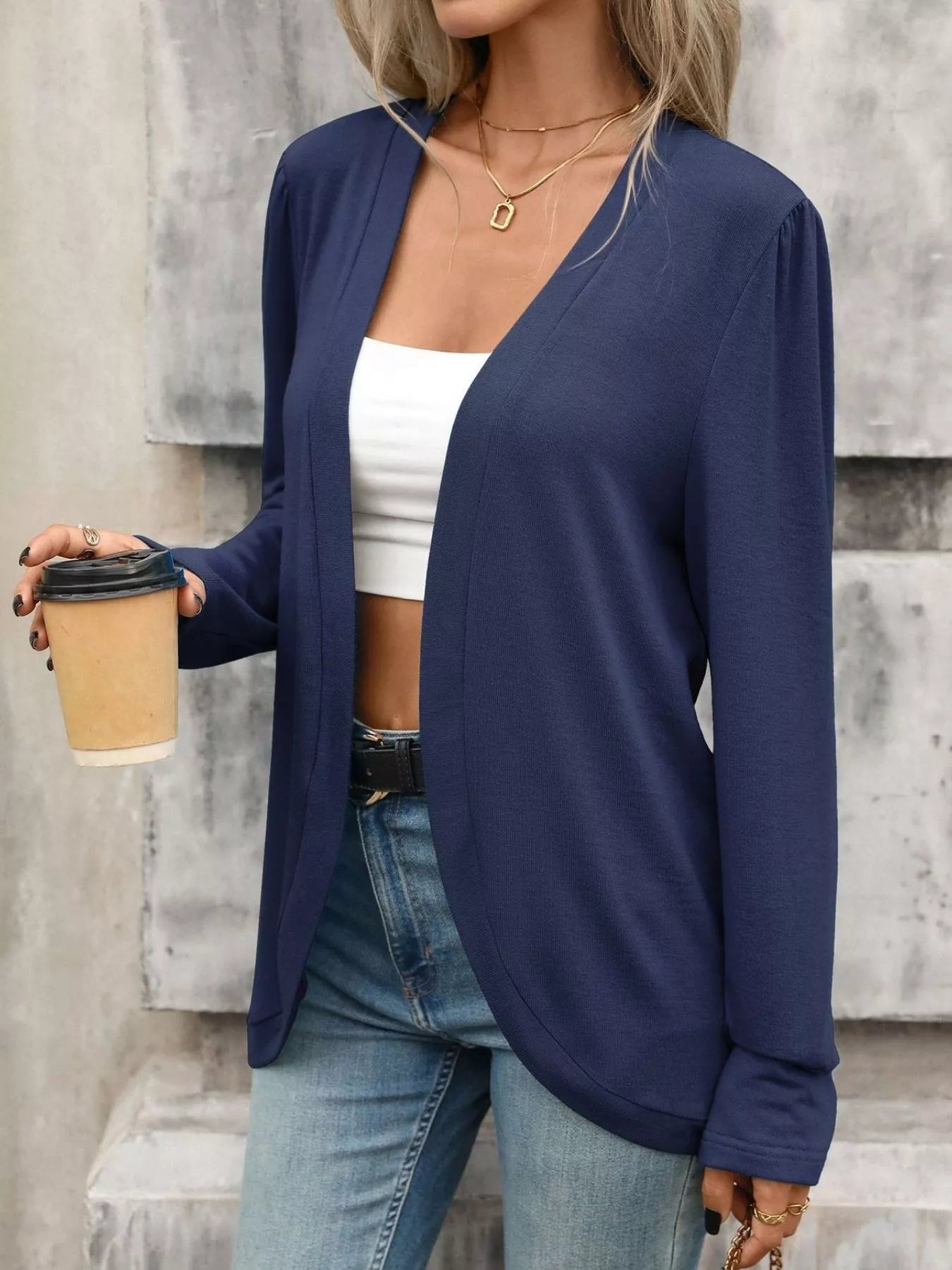 Stylish woman wearing a navy thin open front cardigan with a cropped top and holding a coffee cup.