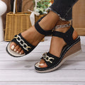 Black open toe wedge sandals with chain detail and mid heels, made of PU leather and rubber.