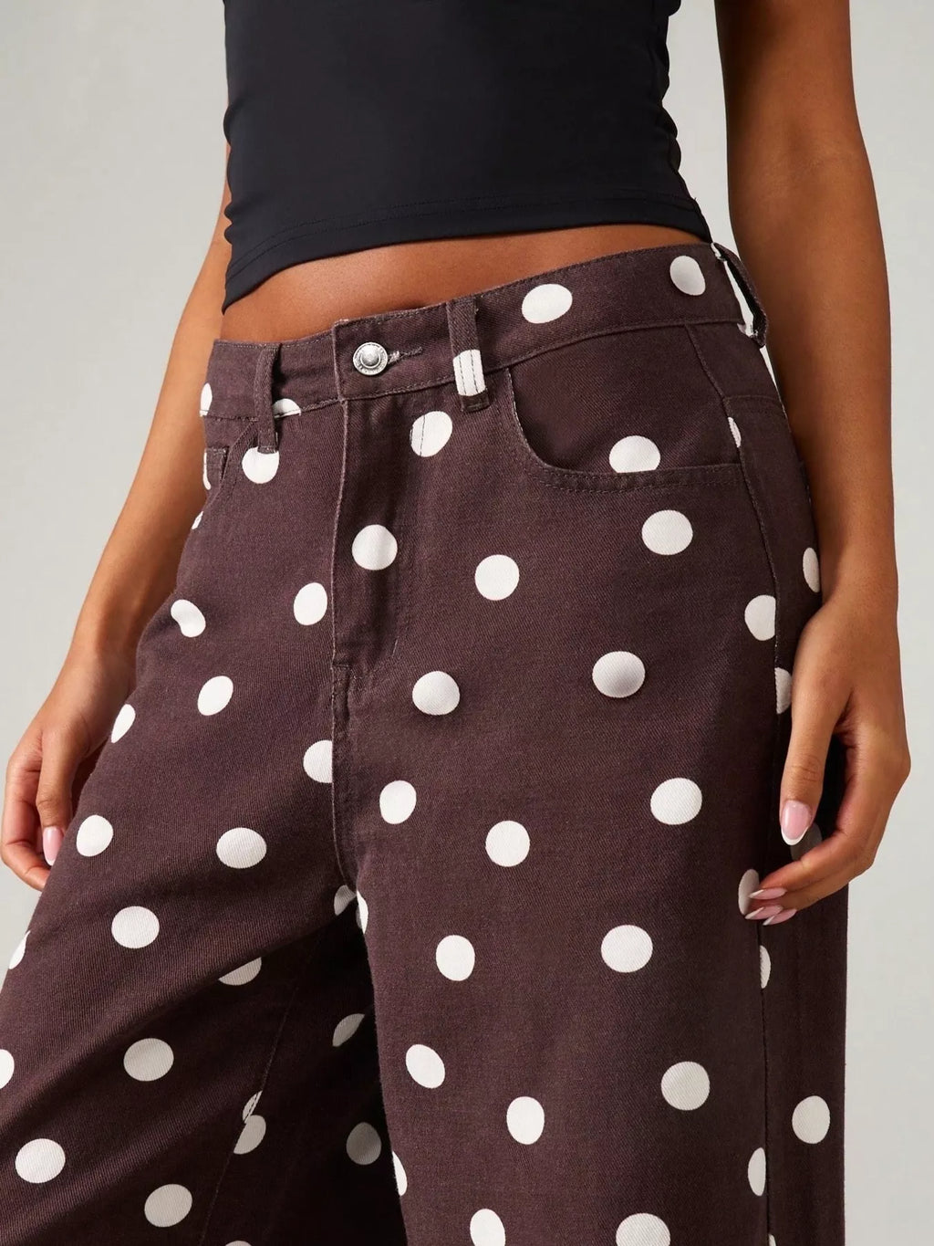 Close-up of trendy polka dot wide-leg jeans with a stylish pocketed design on a model.
