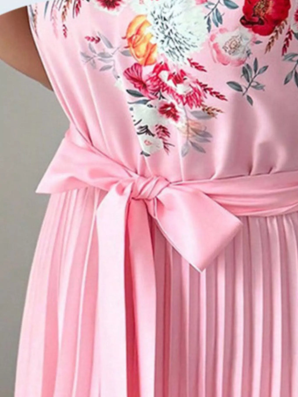 close-up of the summer maxi dress showing halter neck floral print and pleated skirt with bow tie detail