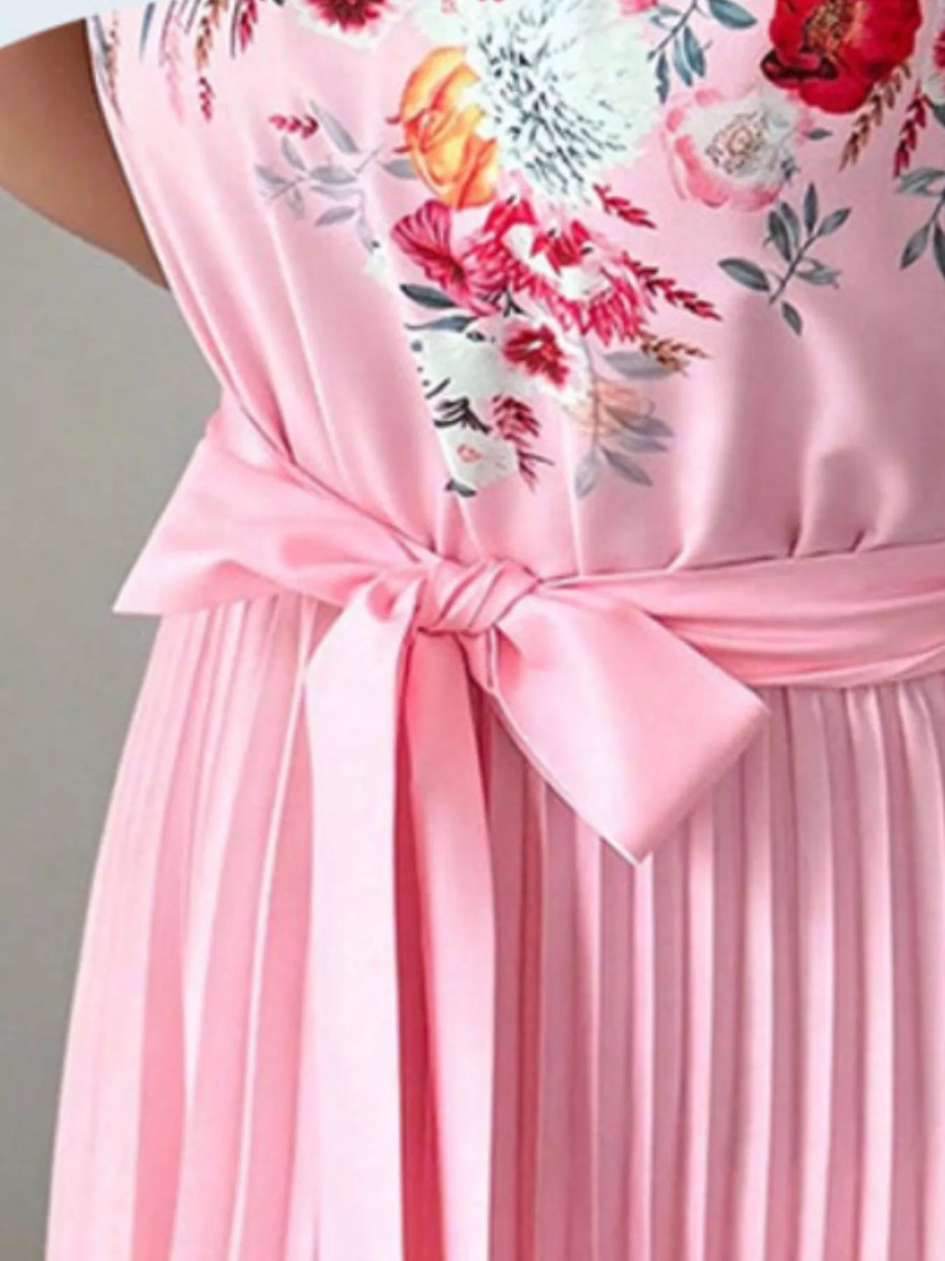 close-up of the summer maxi dress showing halter neck floral print and pleated skirt with bow tie detail