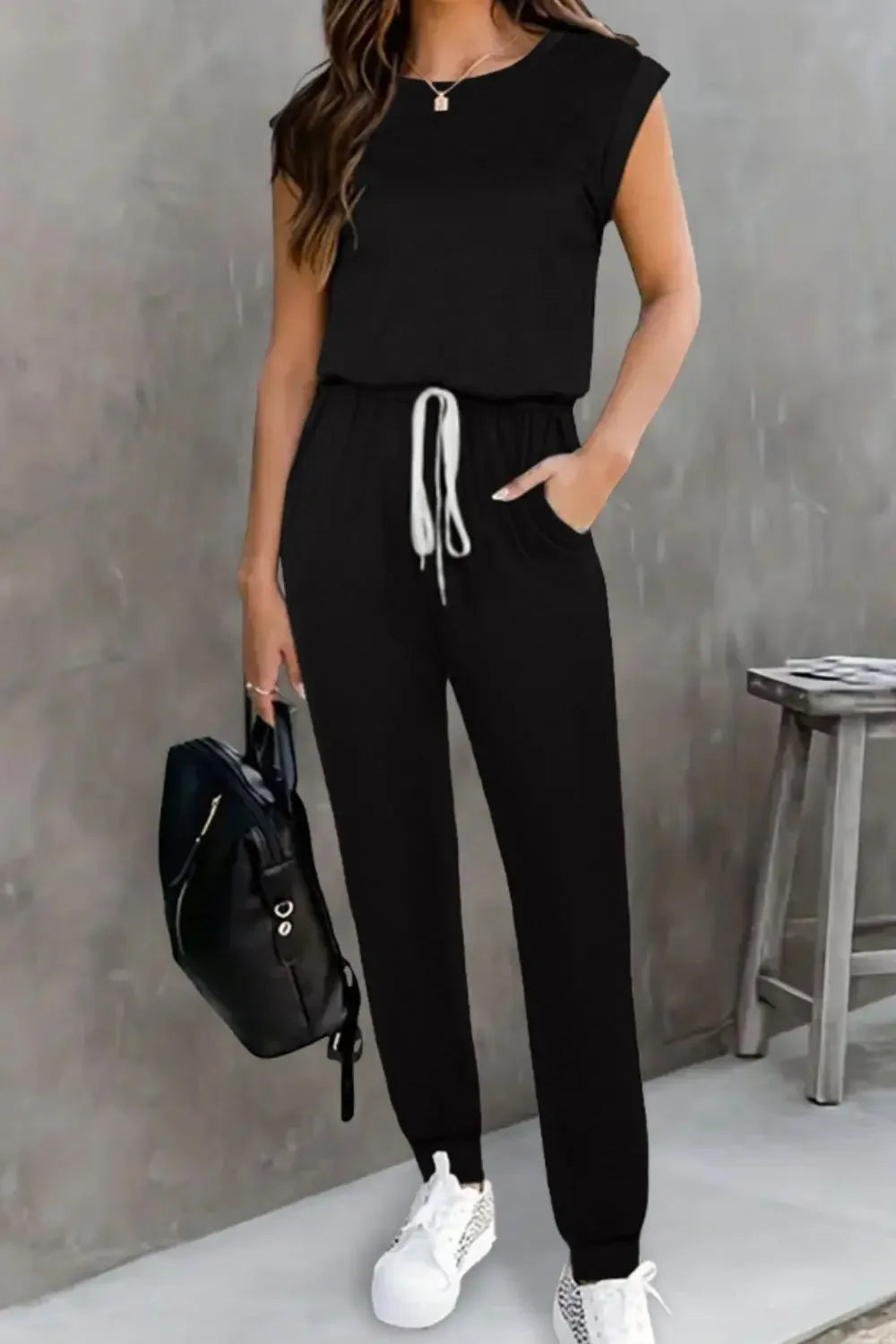 EmpowerEase Sleeveless Drawstring Jumpsuit in black with adjustable waist and stylish pockets for a chic look.