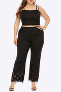 Plus size black pants for women with comfy elastic waist and openwork detail, paired with a matching crop top.