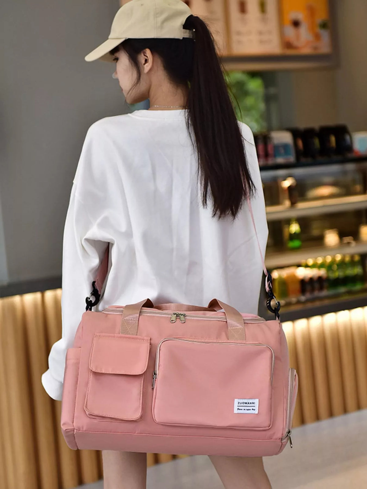 Woman carrying a pink durable travel bag with multiple pockets, designed for convenience and style.