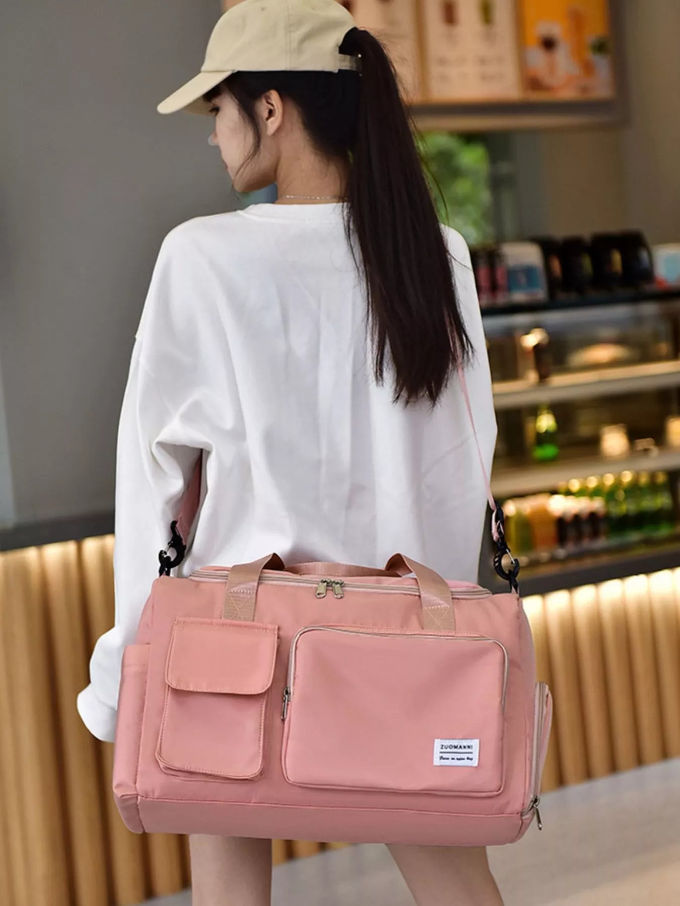 Woman carrying a pink durable travel bag with multiple pockets, designed for convenience and style.