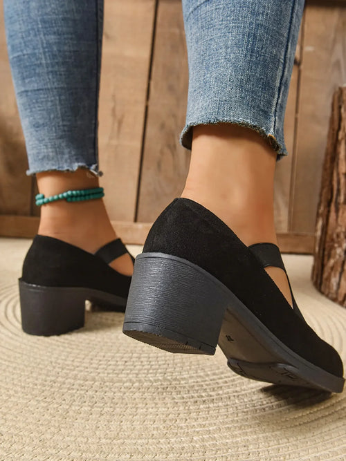 Black Crisscross Block Heel Pumps worn with denim, showcasing the stylish block heel design from a side view.