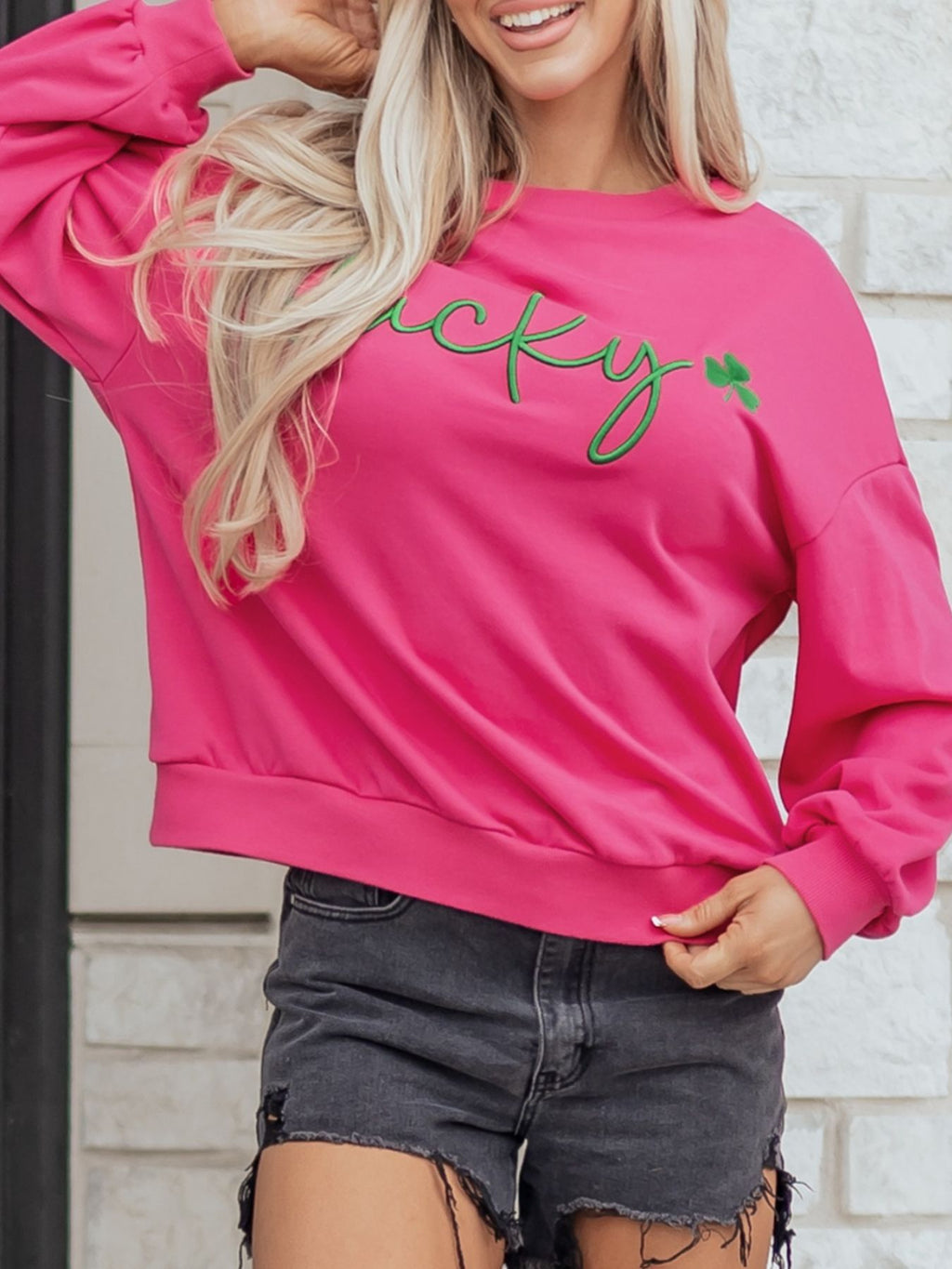 Lucky Clover Embroidered Loose Pullover Sweatshirt in vibrant pink worn with black shorts.
