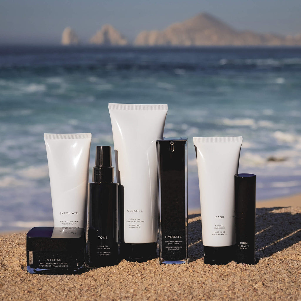 Hyaluronic moisturizer for dry skin among skincare products on a beach setting with ocean in the background.