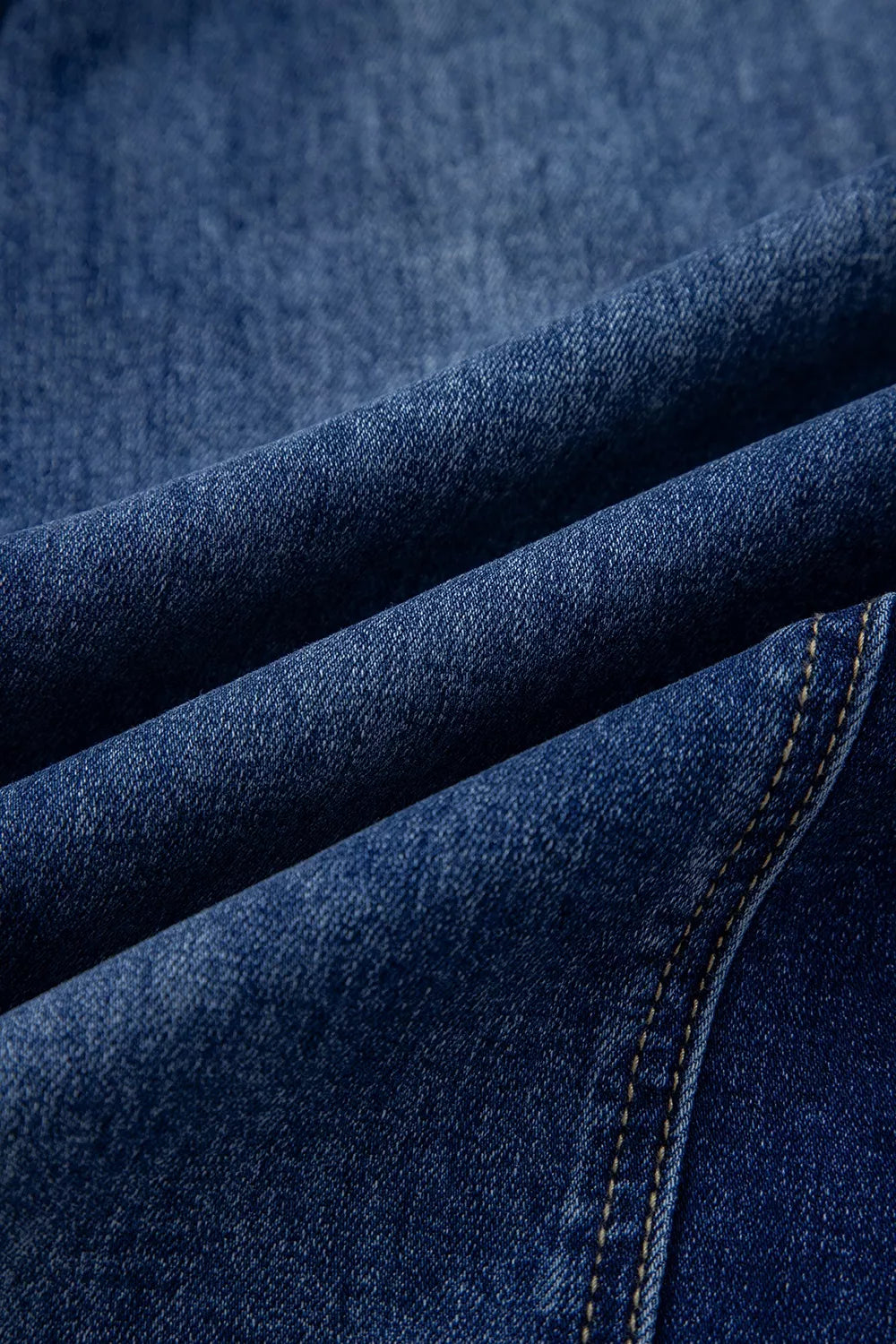 Close-up of the fabric texture of wide leg jeans for women in dark denim with a smooth finish.