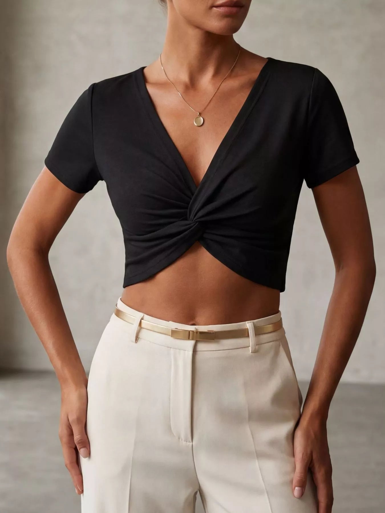 Model wearing a twist front shirt cropped top in black with short sleeves and a twisted design, showcasing a stylish outfit.