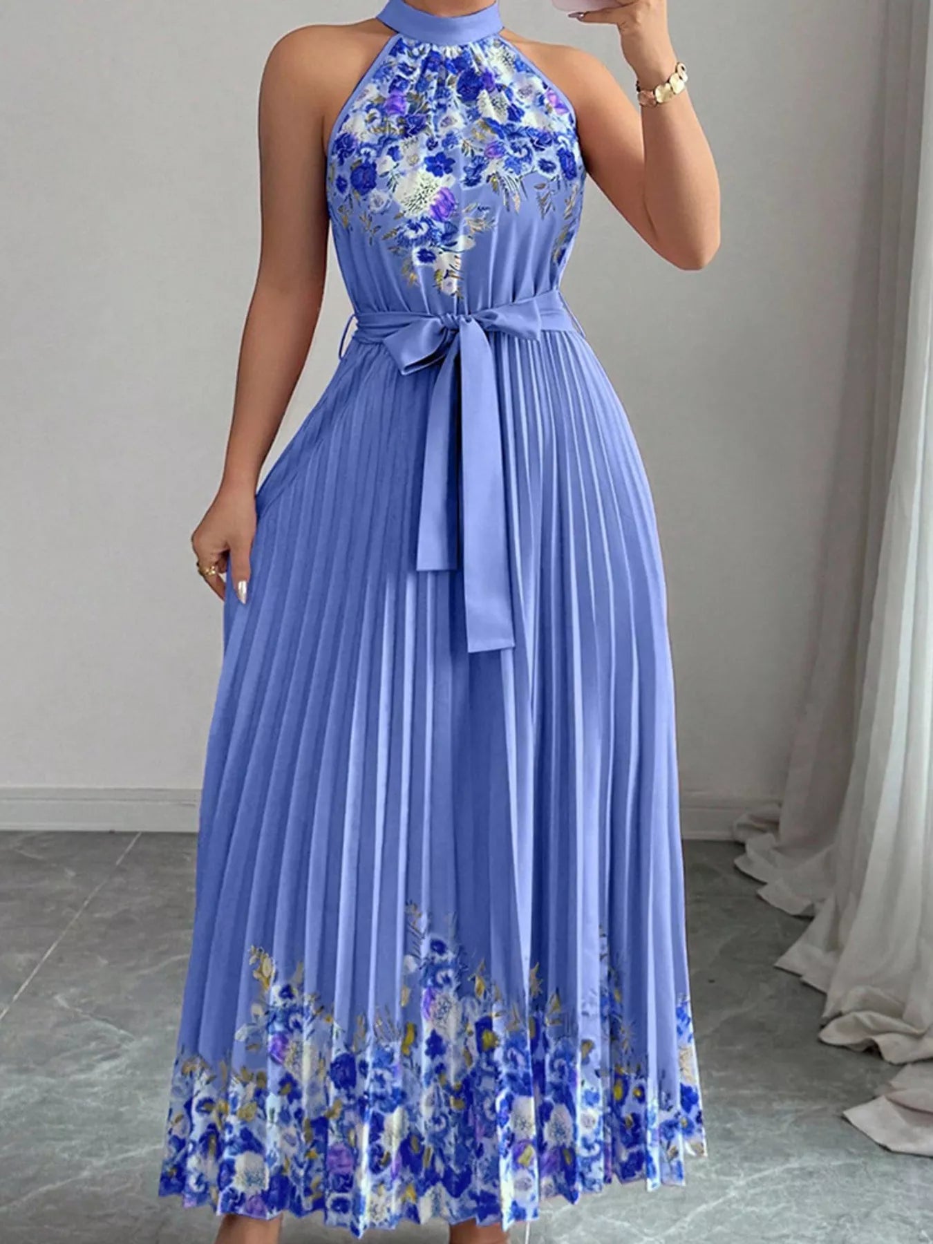 Summer maxi dress featuring a halter neck design, floral print, and pleated skirt in a beautiful shade of blue.