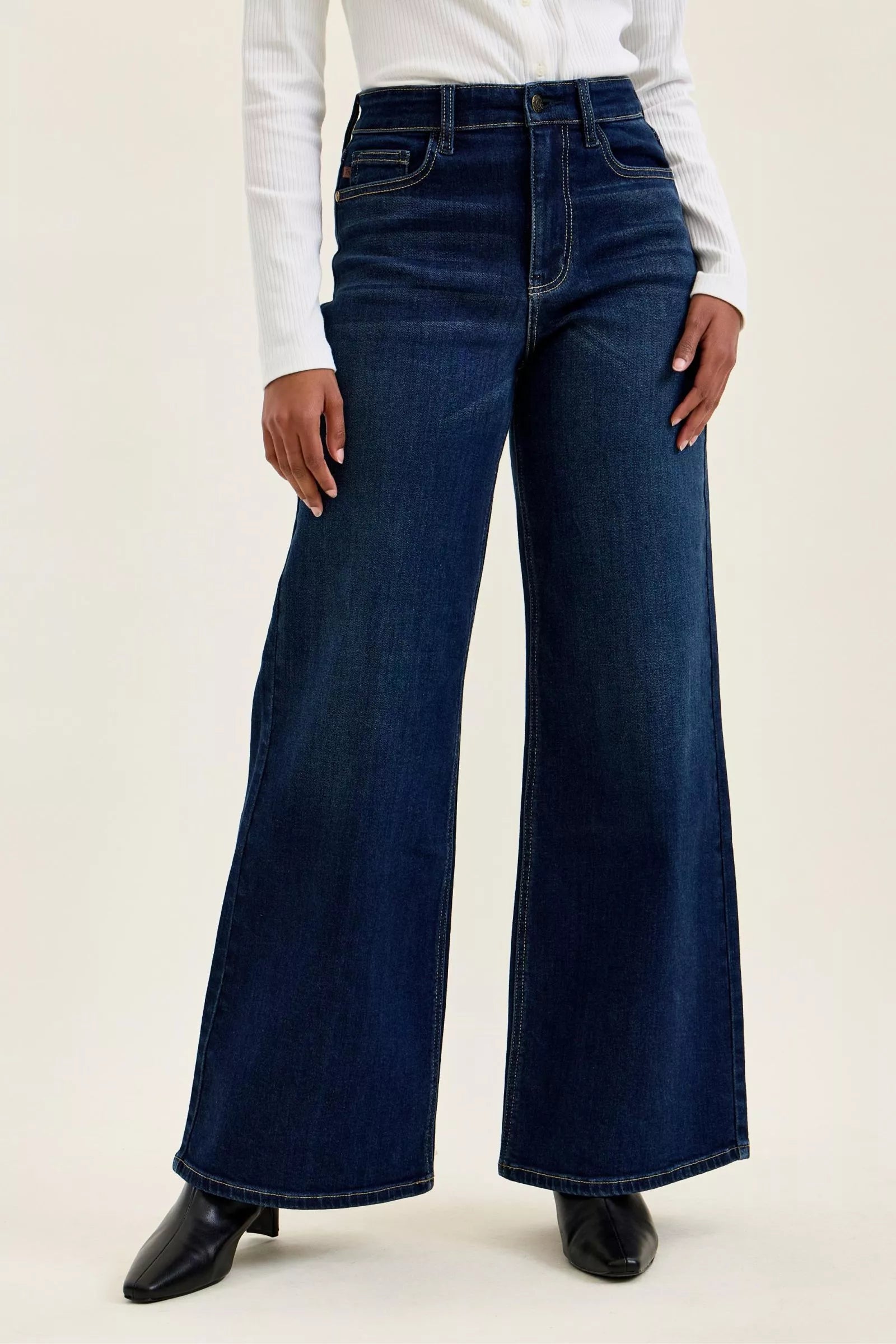 Model wearing dark blue high-waisted wide-leg jeans, showcasing a relaxed fit and classic dark wash style.