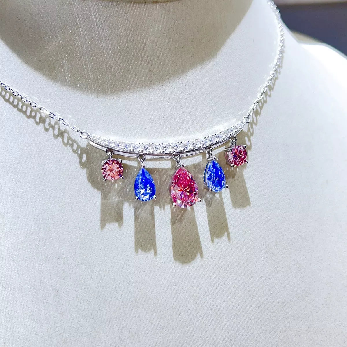 Teardrop silver necklace featuring colorful pink and blue gemstones on a silver chain